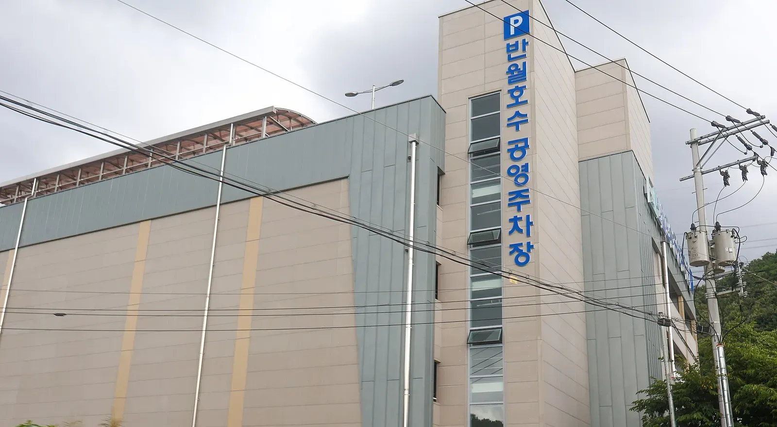 건물형 공영주차장 외벽에 공영주차장 표지가 세로로 붙어 있는 모습