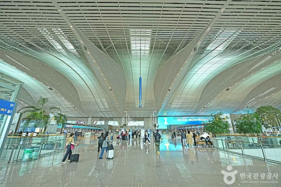 넓은 곡선형 천장 아래 이용객들이 오가는 공항 터미널 중앙 홀