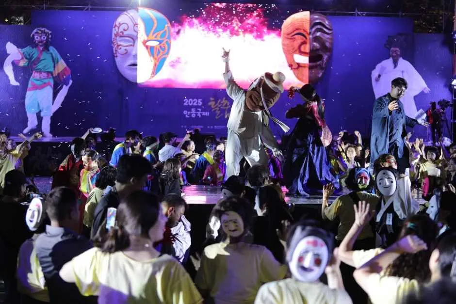 야간 무대에서 불꽃 연출과 함께 탈놀이 공연이 펼쳐지고 관객들이 함께 어우러지는 모습