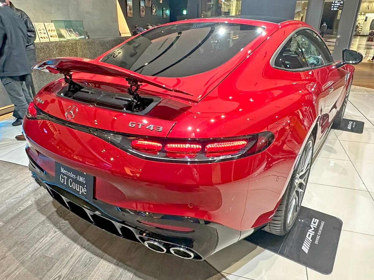 일본 전시장에 놓인 붉은색 메르세데스-AMG GT 43의 후면, 올라간 리어 스포일러와 쿼드 배기구가 보인다