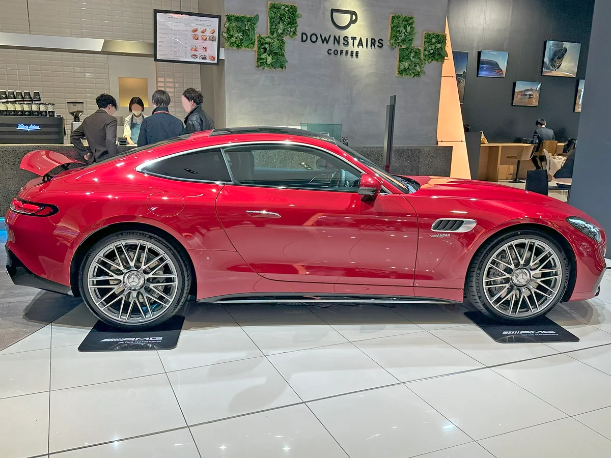 전시장에 놓인 붉은색 메르세데스-AMG GT 43 쿠페의 측면, 긴 보닛과 짧은 데크가 보인다