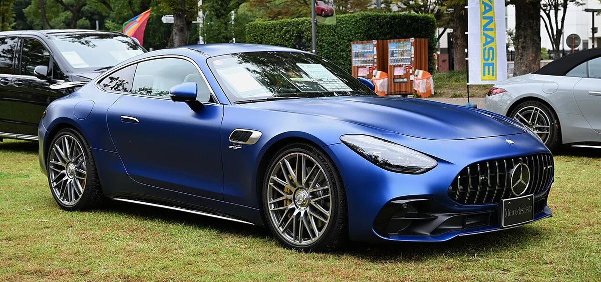 잔디밭에 세워진 파란색 메르세데스-AMG GT 43 쿠페의 측면, 낮은 지붕선과 대형 휠이 보인다