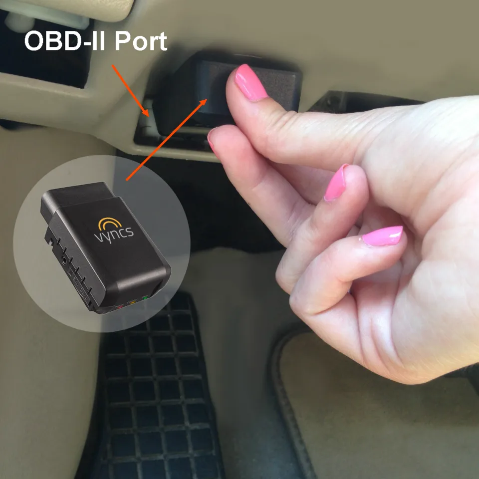 손가락으로 차량 대시보드 하단의 OBD-II 포트를 가리키며 작고 검은 GPS 추적기 장치를 연결하려는 모습, 장치에는 제조사 로고가 표시돼 있다