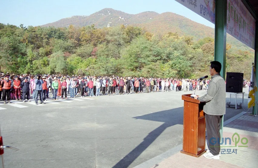수리산 자락 야외무대에서 열린 가을단풍 걷기대회 개회식, 뒤로 단풍이 물든 산줄기가 보인다