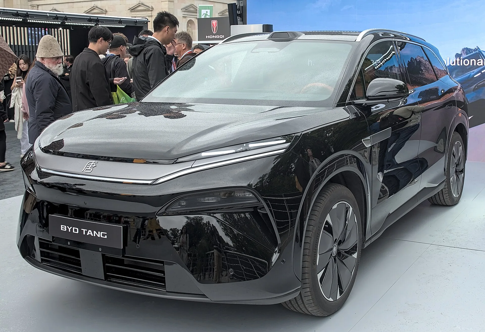 검은색 BYD 탕 L EV 전측면 사진, 전시장에서 관람객들이 지켜보고 있다