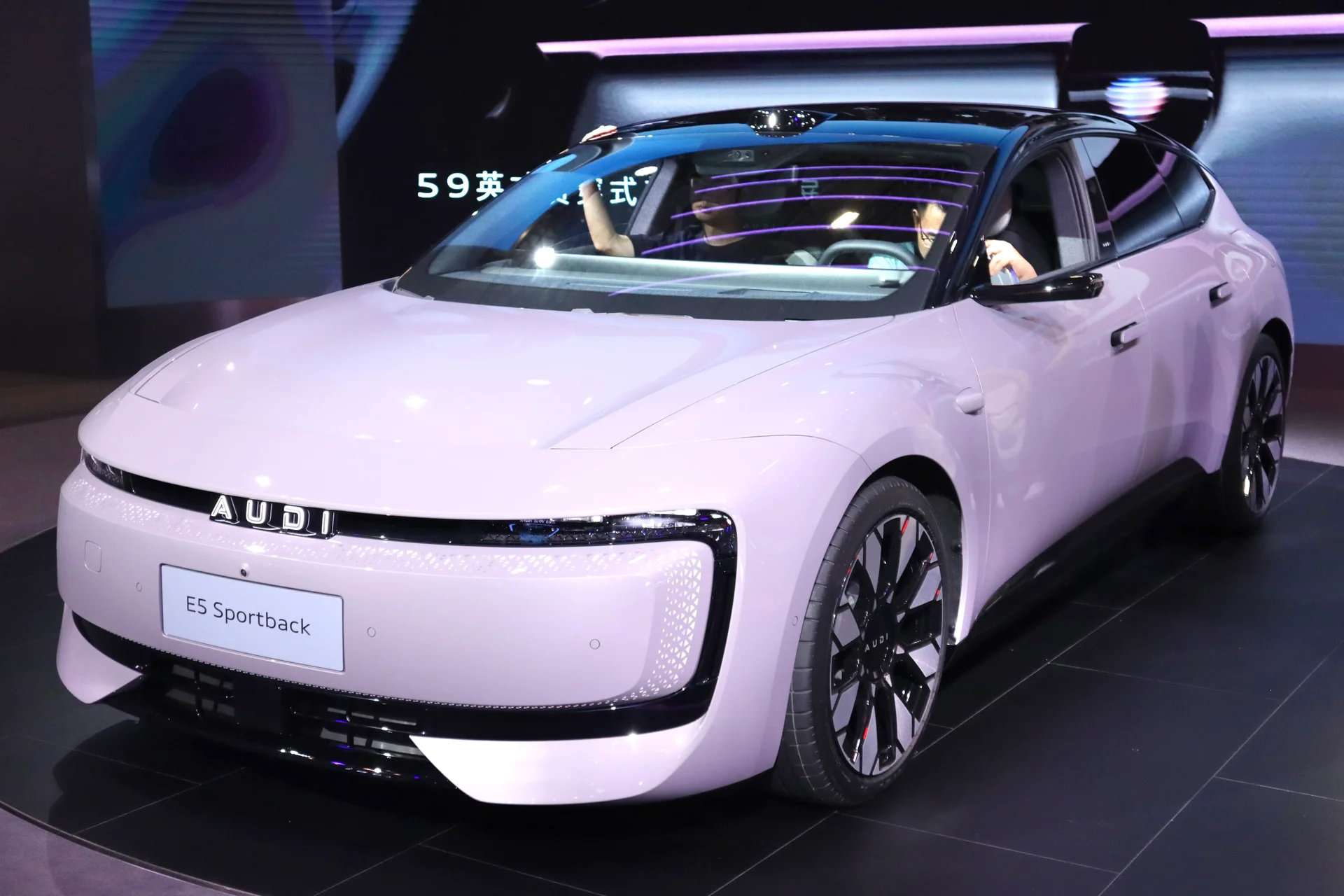 연보라색 아우디 E5 스포트백의 전면부, 네 개 고리 로고 대신 AUDI 레터링이 새겨진 그릴과 E5 Sportback 배지가 보인다