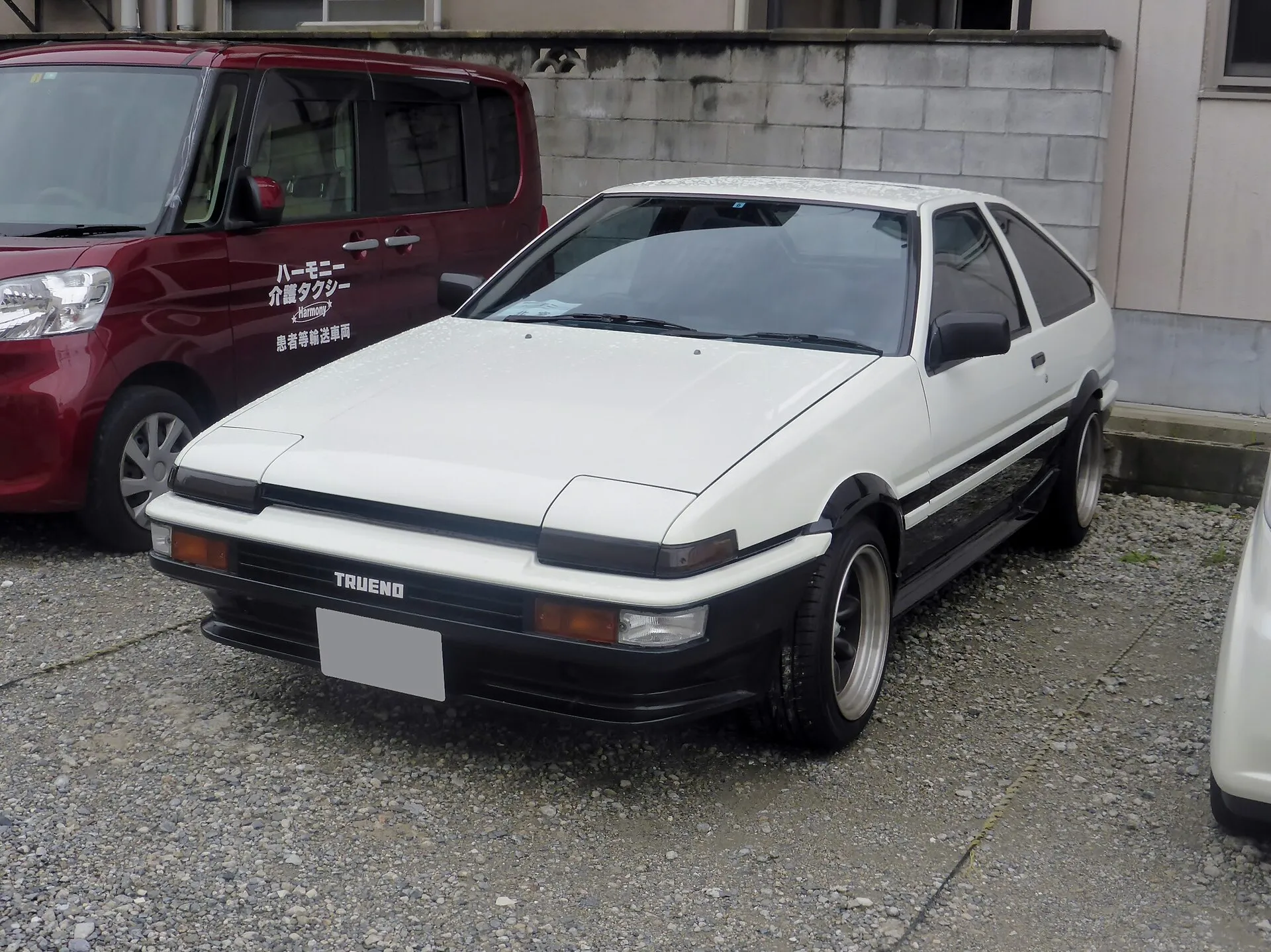 일본 주택가 주차장에 세워진 흰색 토요타 스프린터 트레노 AE86 3도어의 전면 3/4 모습