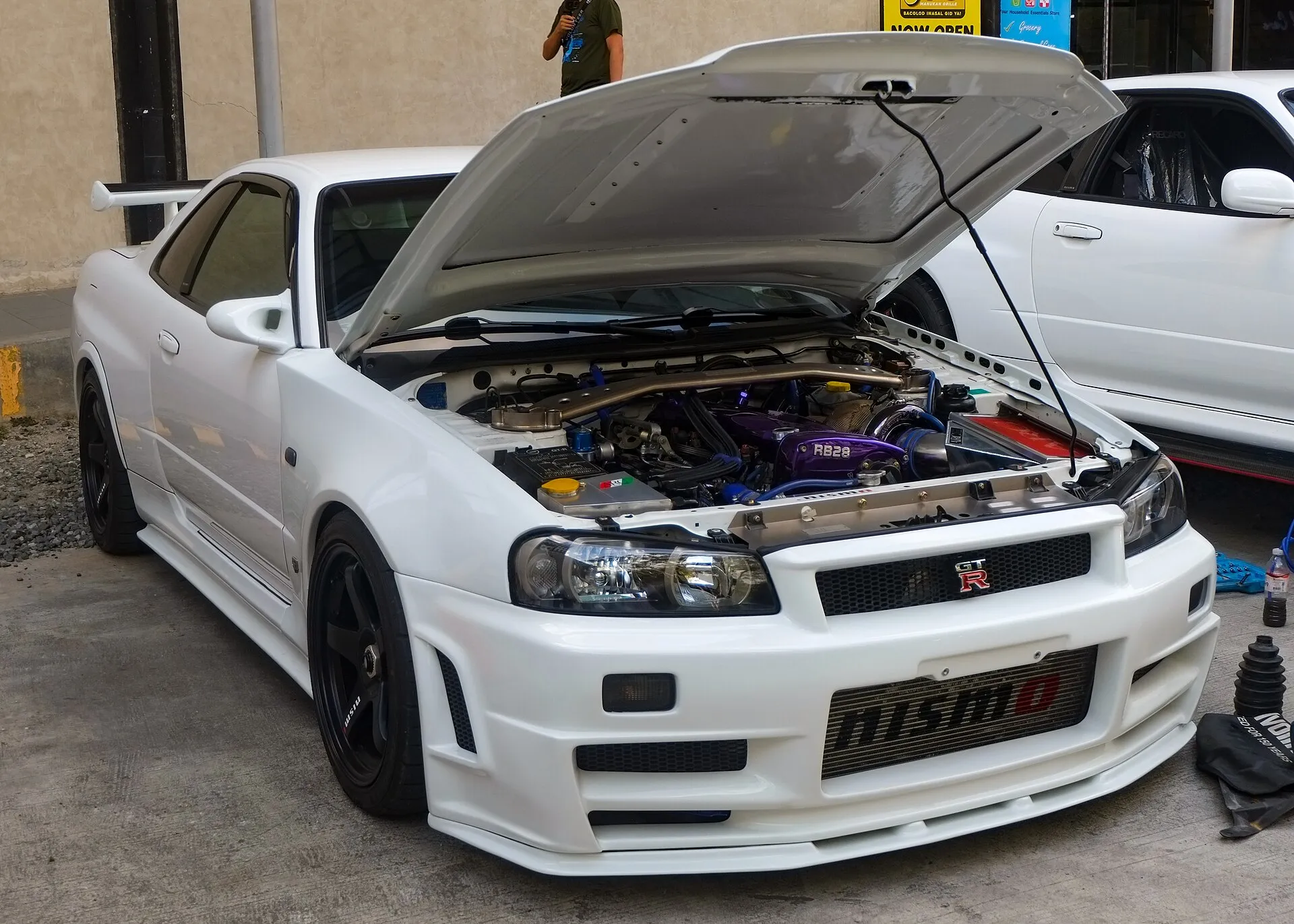 보닛을 연 흰색 닛산 스카이라인 GT-R R34 V-Spec의 전면과 엔진룸