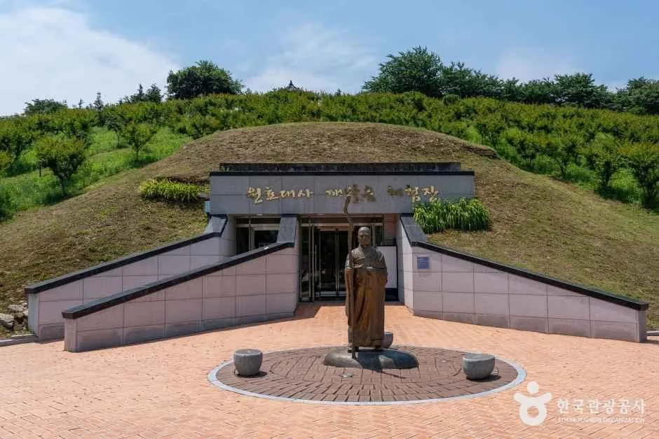 나지막한 둔덕과 광장 앞에 인물 조형물이 서 있는 삼성현역사문화관 외부