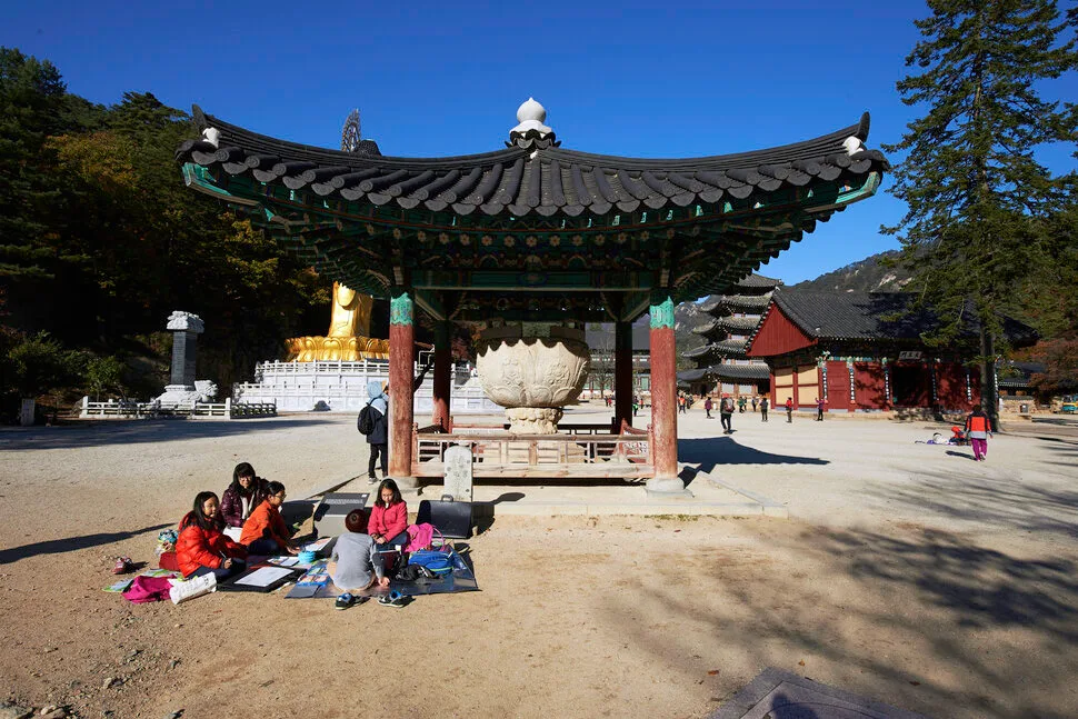 법주사 석련지, 커다란 연꽃 모양 화강암 돌그릇이 정자 아래 놓여 있고 뒤로 팔상전과 금동미륵대불이 보인다