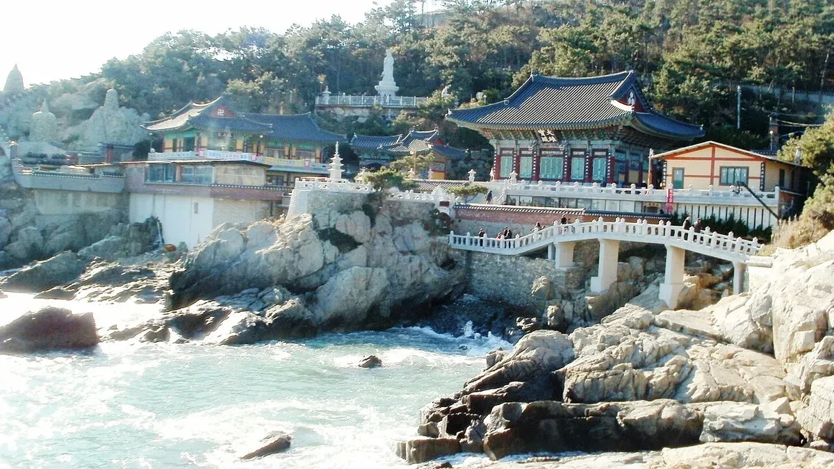 바위 해안 위에 이어진 해동용궁사 전각과 흰 다리, 부서지는 파도