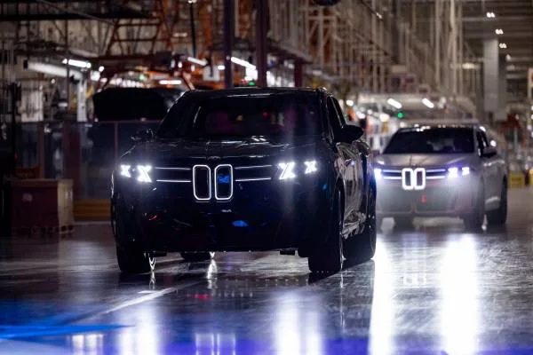 야간 스파르탄버그 공장에서 더블-X 헤드램프를 밝힌 신형 BMW X5 두 대가 나란히 서 있는 모습