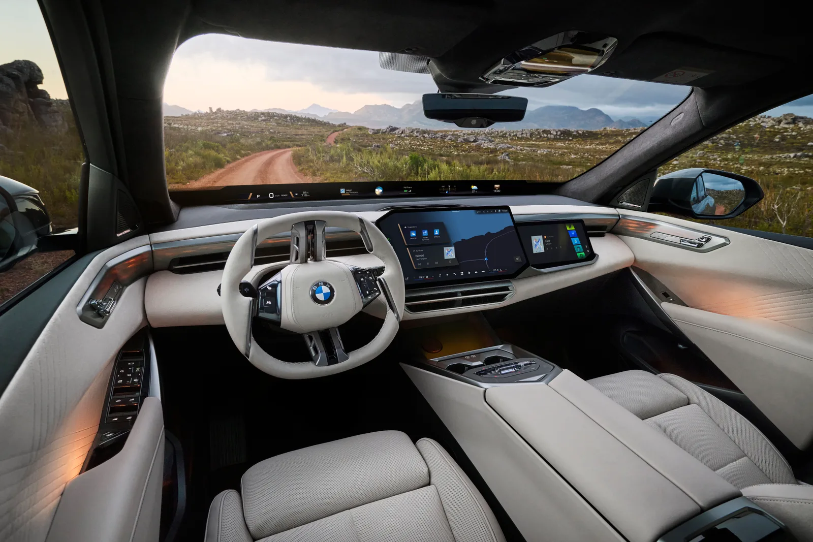 신형 BMW X5 실내, 2-스포크 스티어링 휠과 대시보드를 가로지르는 대형 디스플레이 및 파노라마 비전이 보인다