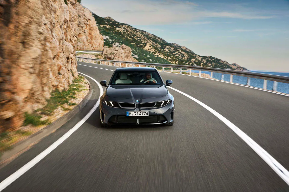 회색 신형 BMW 3시리즈 세단이 해안 도로 커브에서 정면으로 달리는 모습