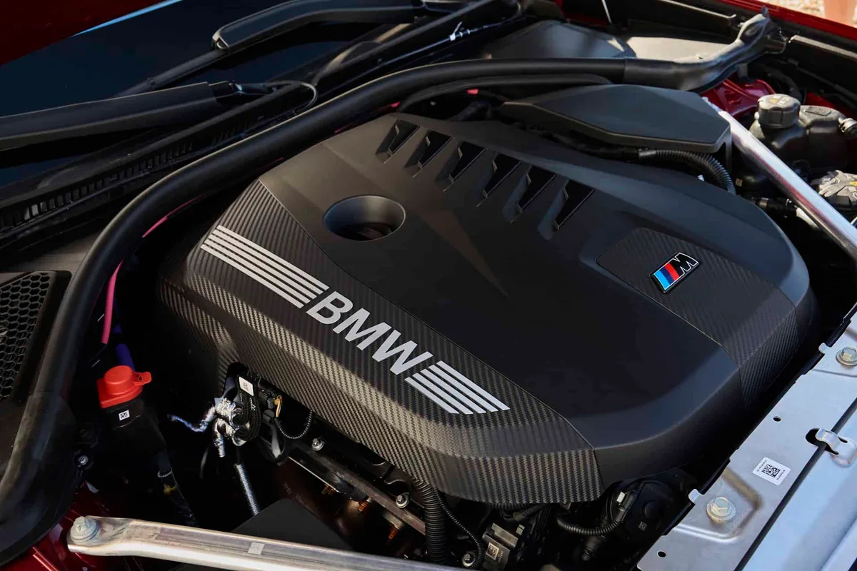 붉은 차체 보닛 아래에 놓인 BMW 3.0리터 직렬 6기통 엔진과 M 로고가 있는 카본 무늬 커버