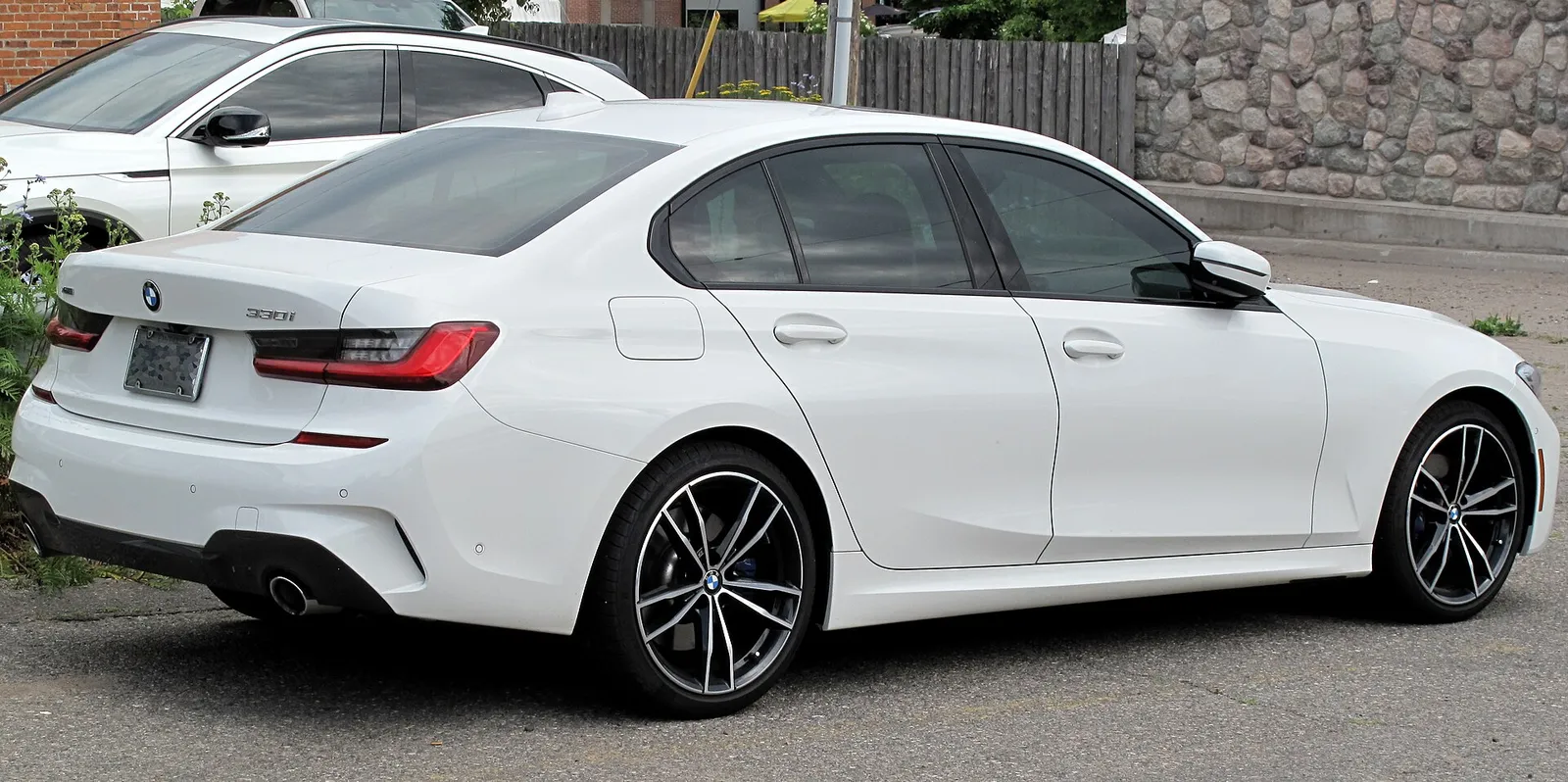 흰색 BMW G20 세대 3시리즈 330i xDrive의 후면과 측면, 세로형 테일램프와 듀얼 배기구가 보인다