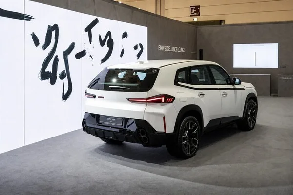 BMW XM 레이블 후측면, 화이트 색상, 붓글씨 캘리그래피 작품이 걸린 프리즈 서울 전시장