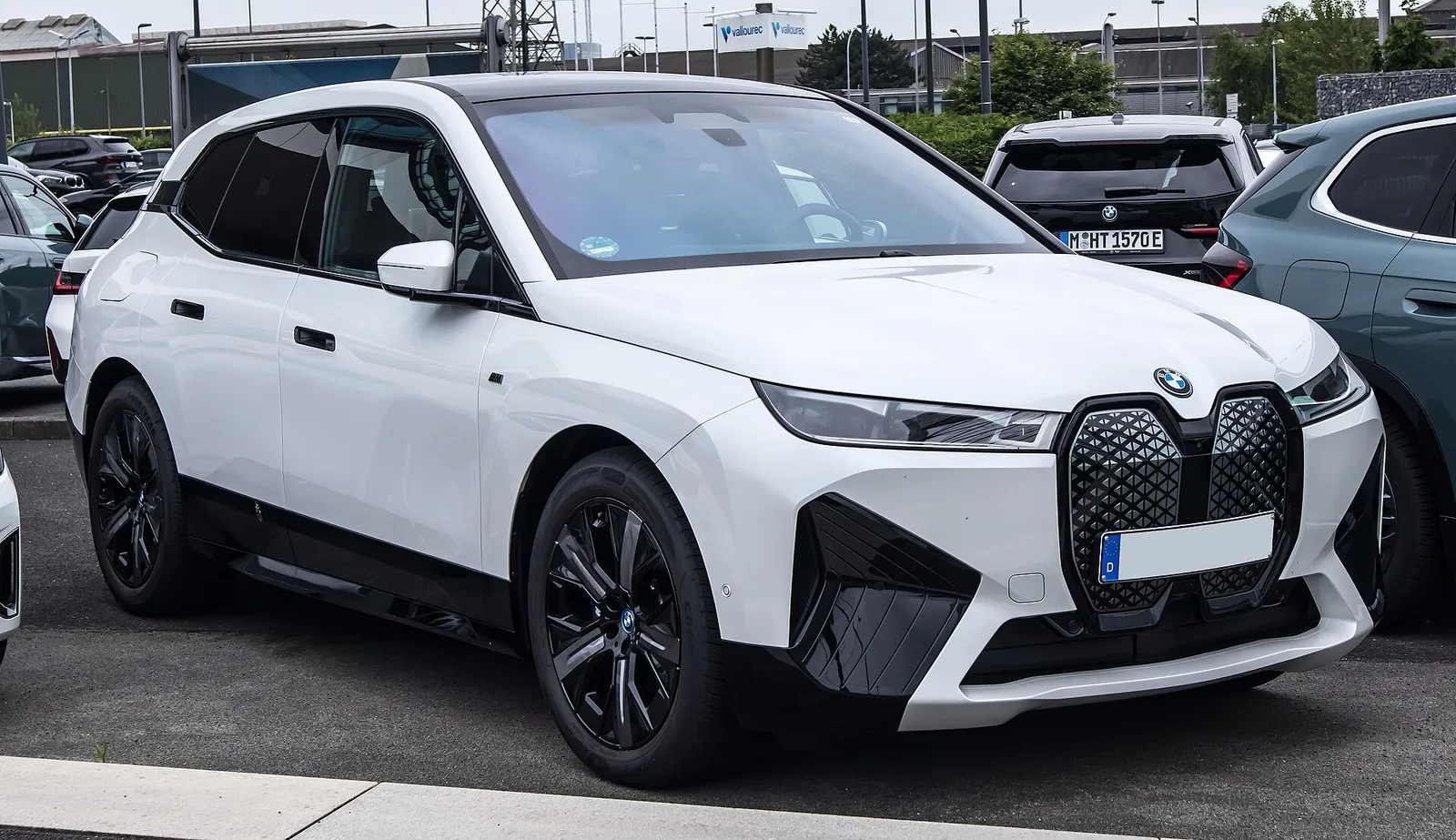 흰색 BMW iX 전면, 대형 키드니 그릴과 슬림한 헤드램프가 보인다