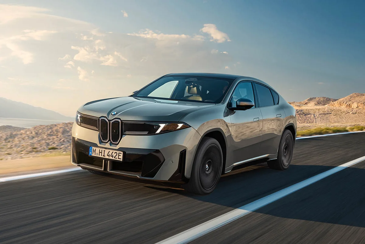 회색 BMW iX4 50 xDrive가 도로를 달리는 전면 3/4 모습, 쌍둥이 키드니 그릴과 슬림한 헤드램프가 보인다