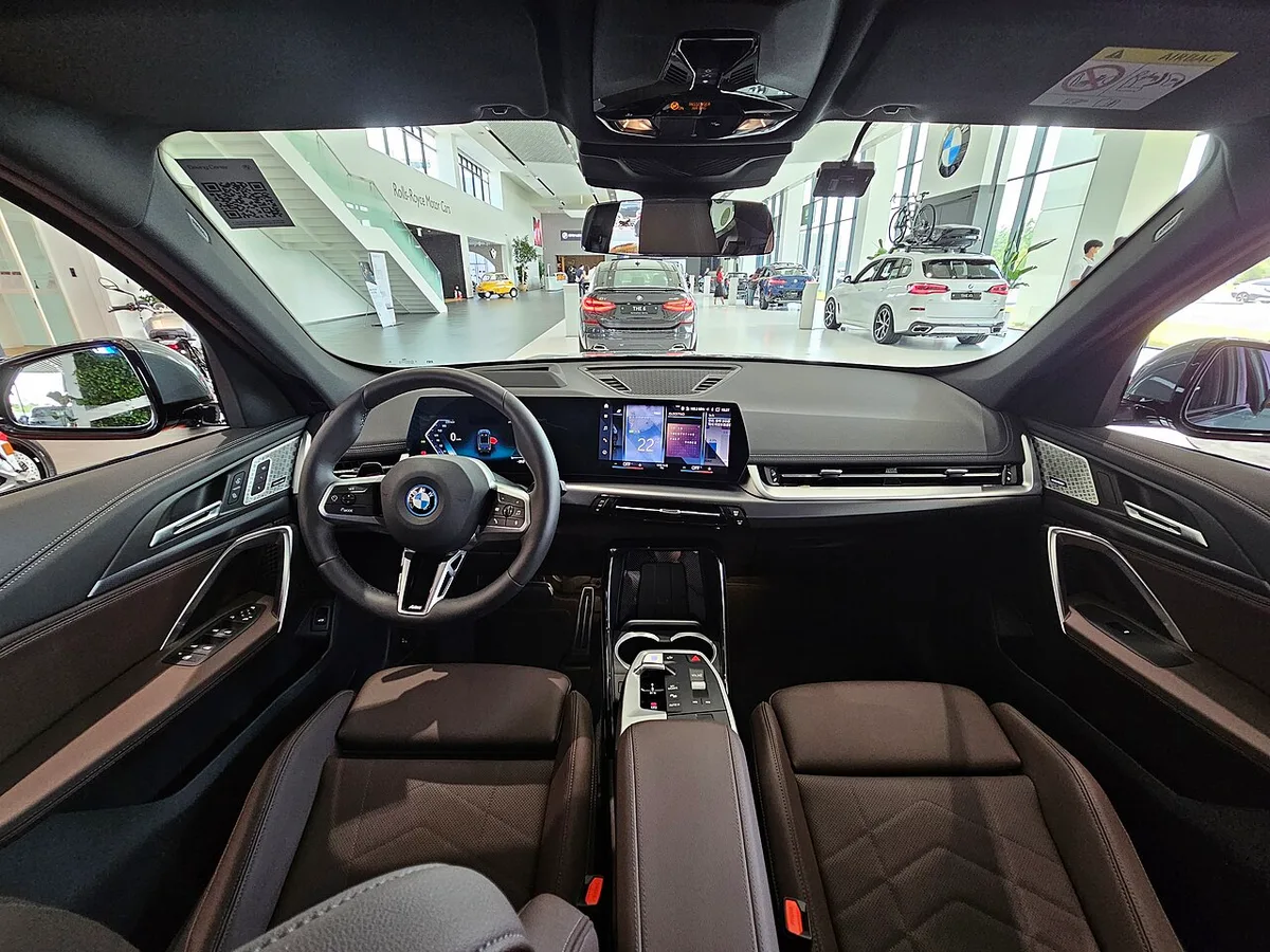 갈색 가죽 시트와 곡면 디스플레이가 보이는 BMW iX1 xDrive30 M 스포츠의 앞좌석 실내