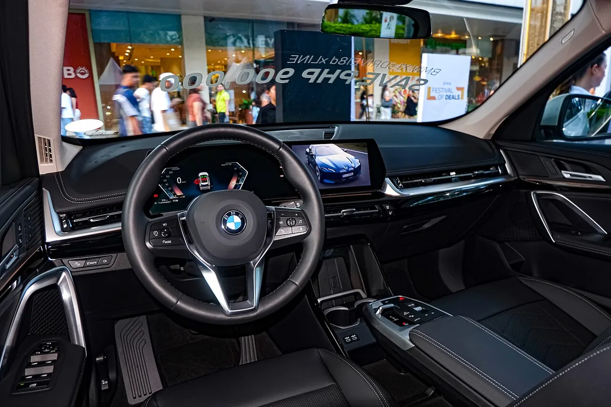 핸들과 곡면 디스플레이, 센터 콘솔이 보이는 BMW X1 sDrive18d xLine의 운전석 쪽 실내
