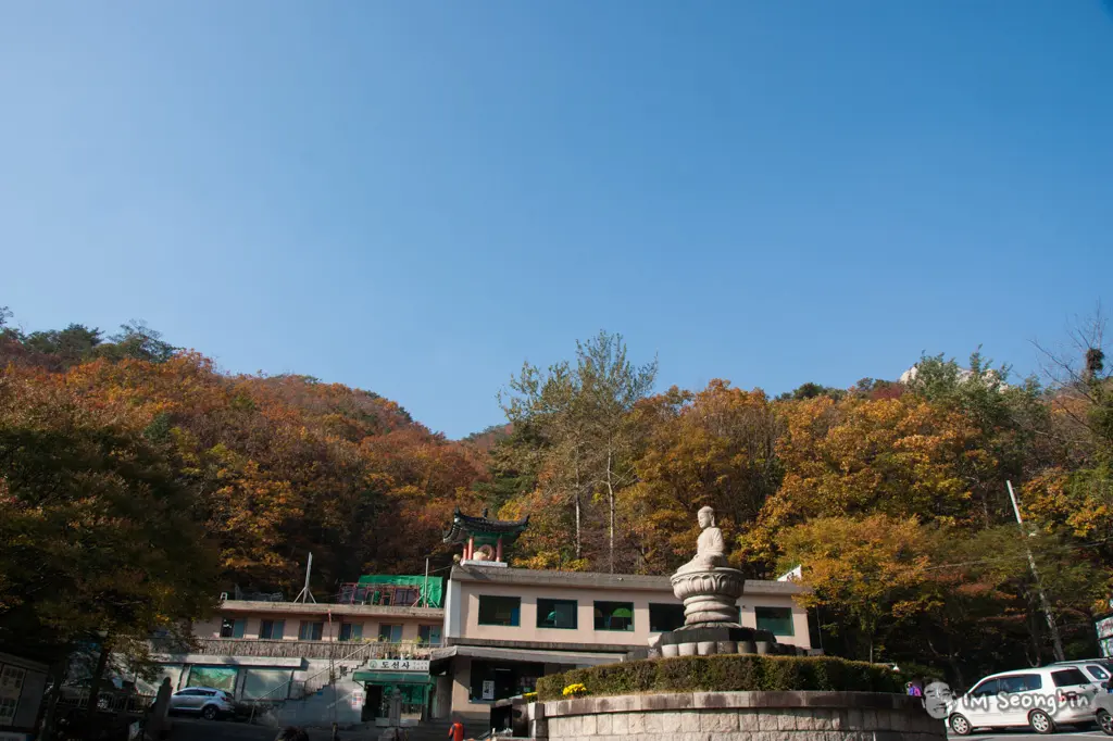 주황·노랑 단풍이 든 산자락 아래 불상과 건물이 보이는 북한산 일대