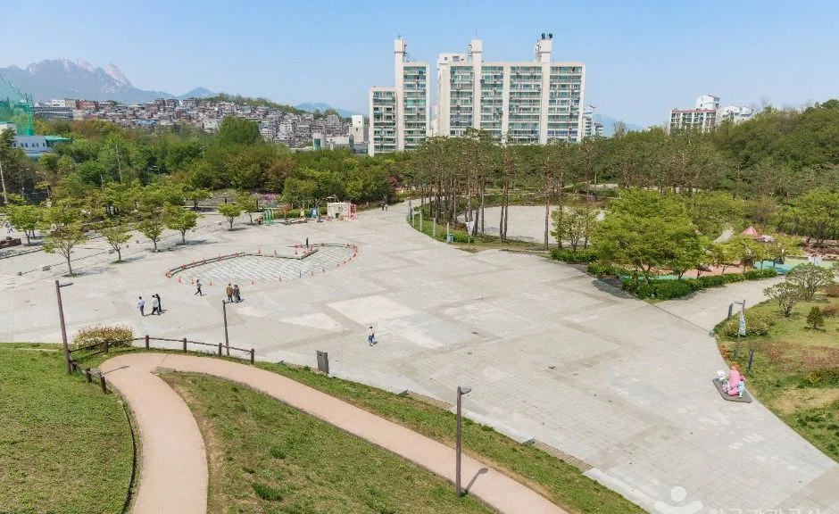 공원 광장 너머로 북한산 봉우리가 보이는 풍경
