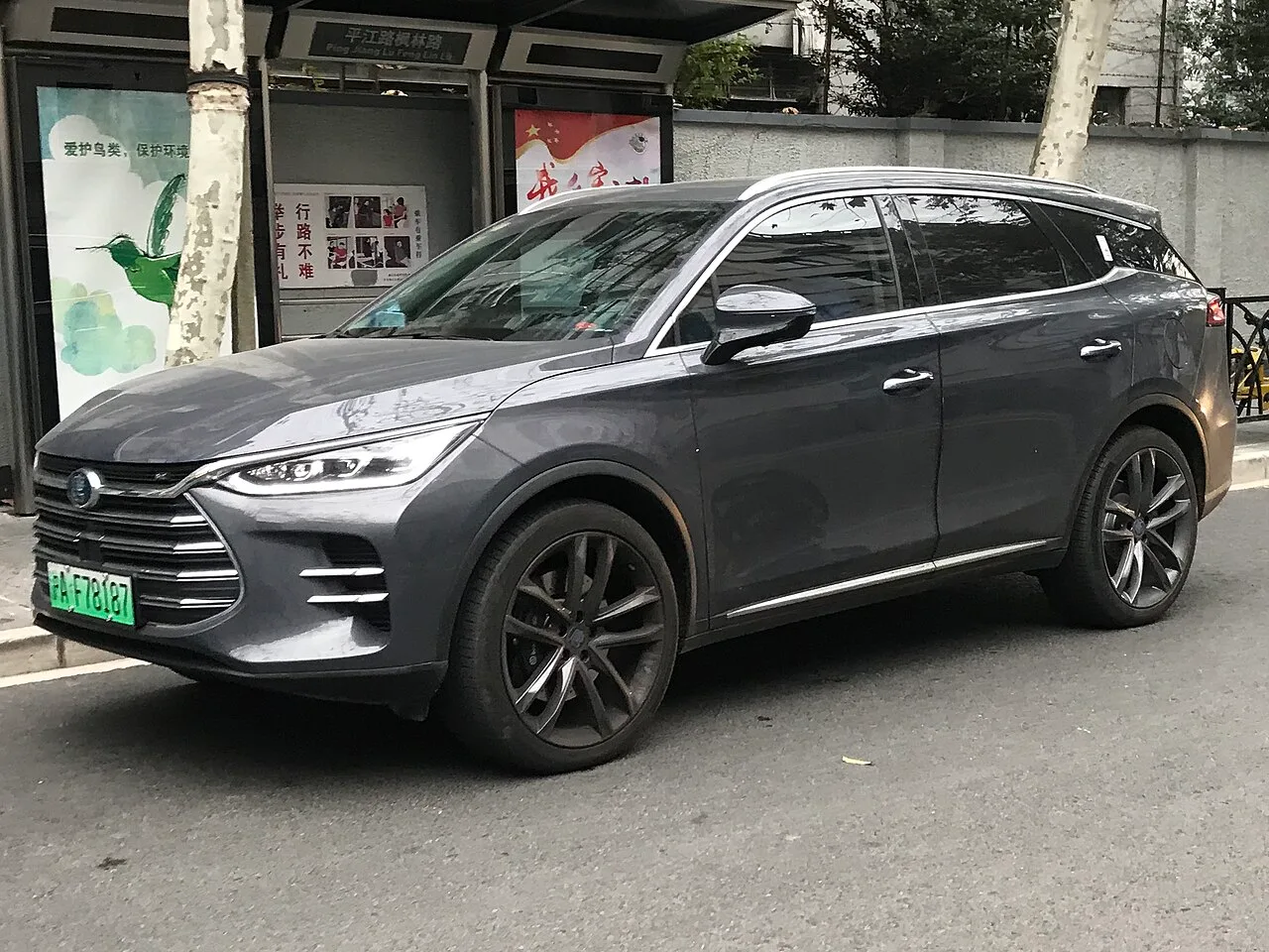 회색 BYD 탕 SUV의 전면 및 측면 모습, 대형 그릴과 크롬 루프레일이 보인다