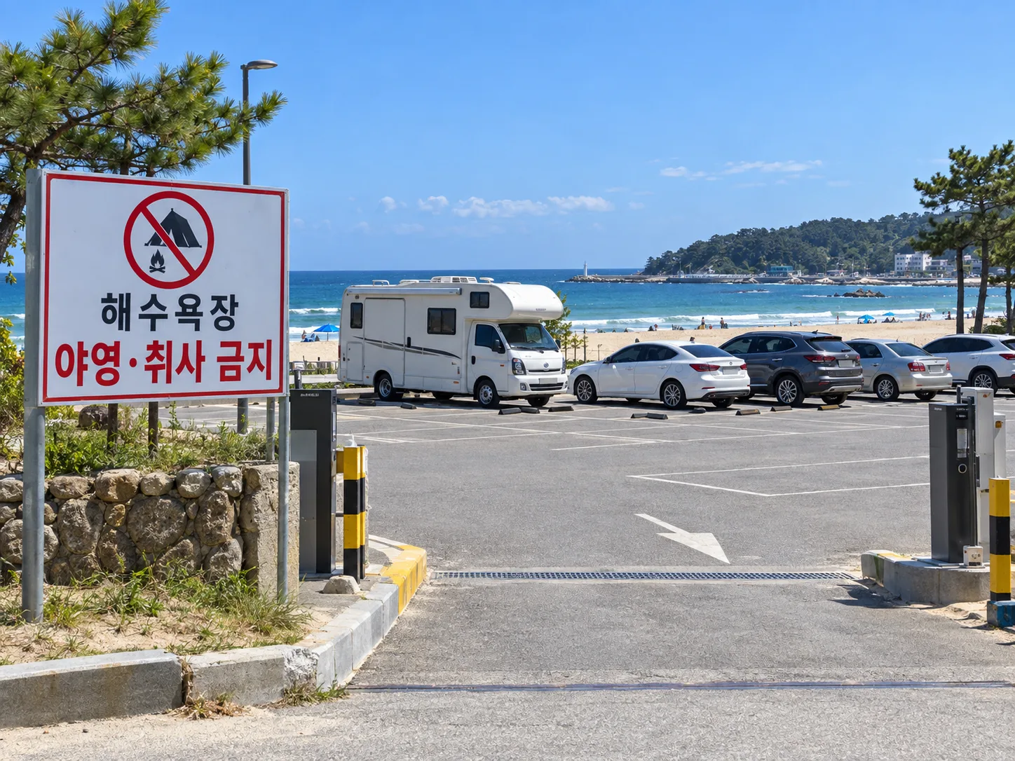 한국 동해안 해수욕장 인근 공영주차장, 캠핑카와 승용차 여러 대가 주차되어 있고 야영·취사 금지 안내 표지판이 세워진 낮 풍경