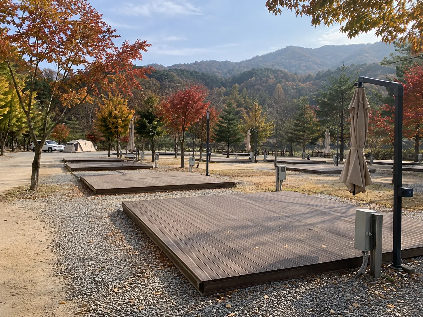 평일 낮 잘 정비된 오토캠핑장의 데크 사이트 여러 곳이 텅 비어 있고 이용객이 거의 보이지 않는 한산한 가을 풍경