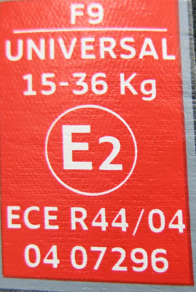 붉은 바탕에 F9 UNIVERSAL 15-36 Kg, E2 원 안에 ECE R44/04 승인 번호가 인쇄된 카시트 승인 라벨