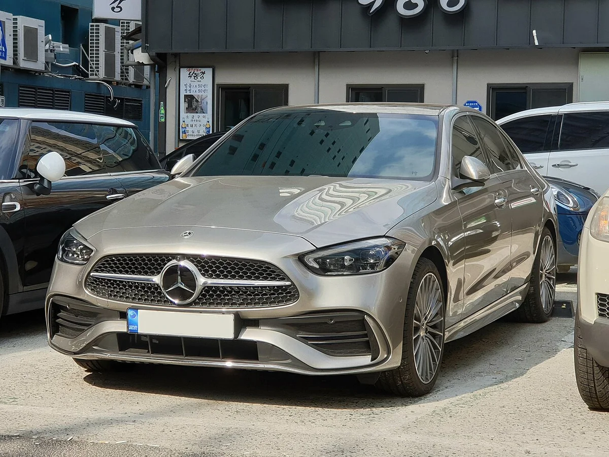 건물 앞 주차 공간에 정면으로 선 은회색 벤츠 C 300 AMG 라인(W206)