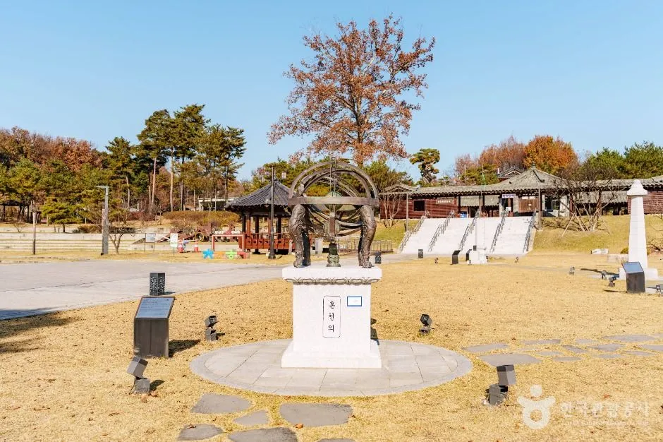 돌로 둥글게 마감한 터에 기구 모양 조형물이 서 있는 초정행궁 야외 정원