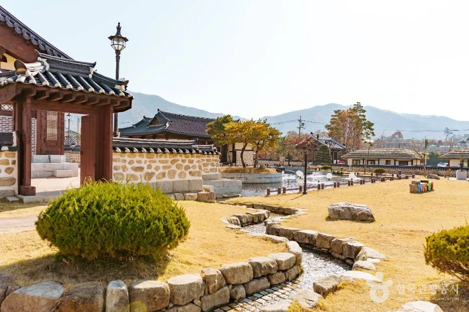 돌로 쌓은 작은 물길이 흐르고 뒤로 한옥과 산이 보이는 행궁 마당