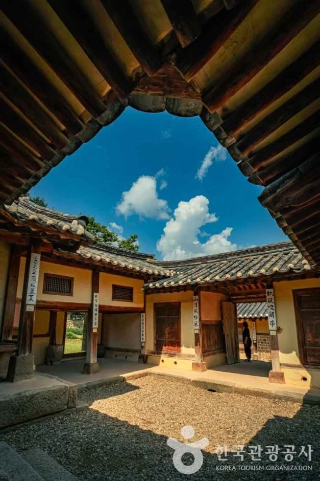 고택 건물 사이로 푸른 하늘과 기와지붕이 보이는 세로 사진