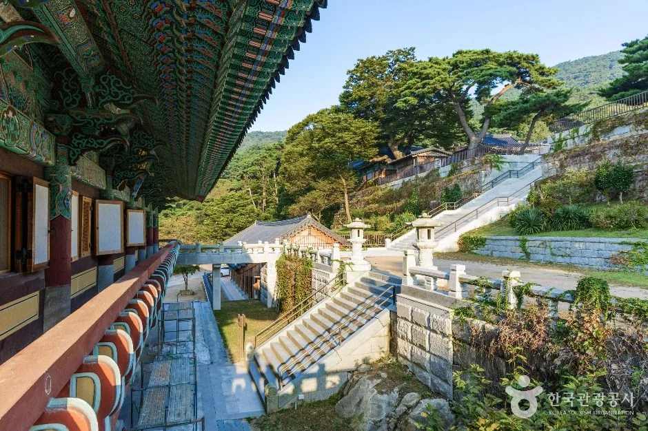 붉은 단청 처마 아래로 석등과 계단이 내려다보이는 사찰 경내