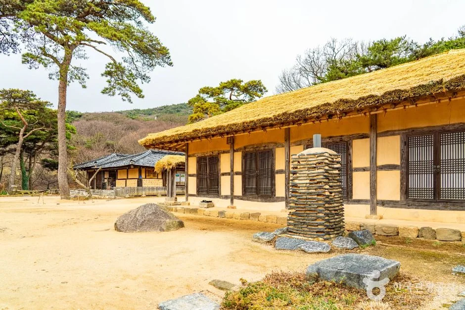 ㄷ자로 이어진 초가지붕 건물과 흙마당