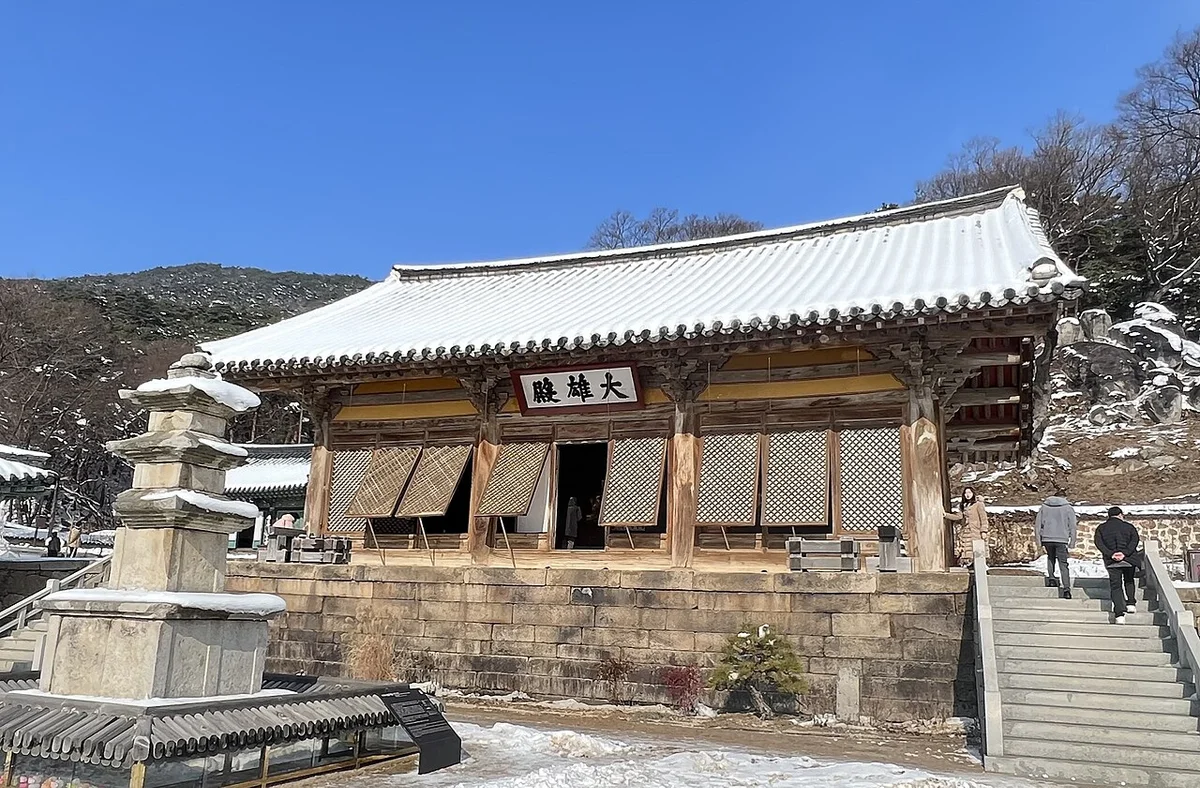 지붕과 계단 가장자리에 눈이 남은 수덕사 대웅전과 삼층석탑
