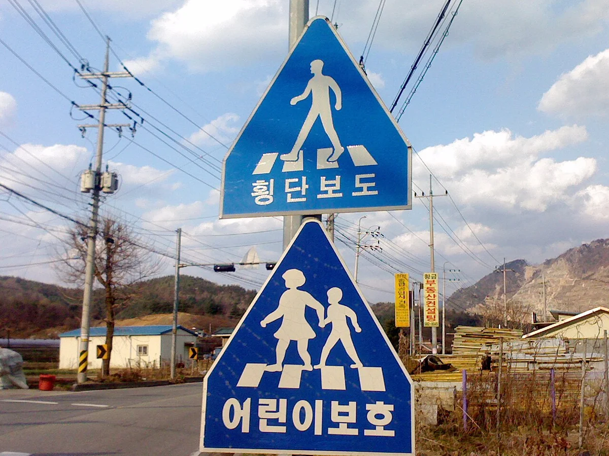 횡단보도 표지와 어린이 보호 표지가 함께 세워진 도로변 파란 표지판