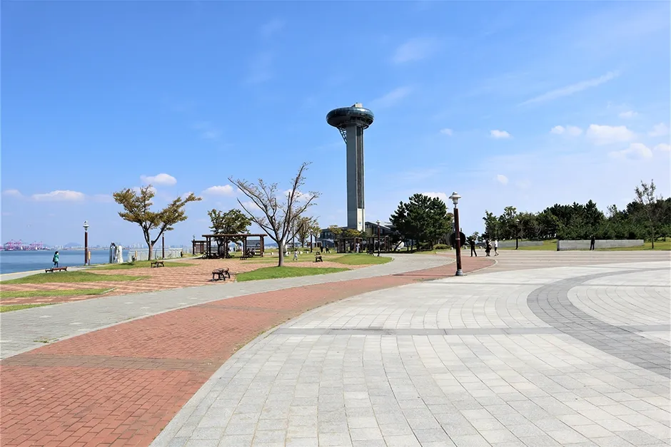 푸른 하늘 아래 산책로 너머로 솟은 원형 전망대 타워