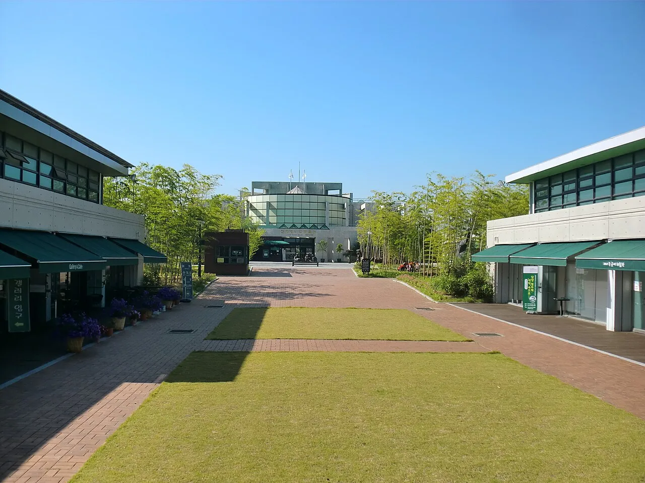 한국대나무박물관 외관, 대나무가 심긴 화단과 벽돌 포장 마당을 갖춘 저층 전시관 건물