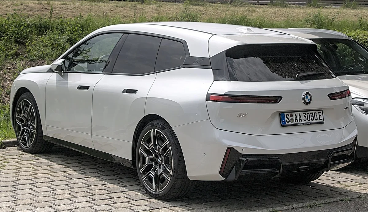 흰색 BMW iX의 후면 3/4 모습, 독일 번호판이 보인다