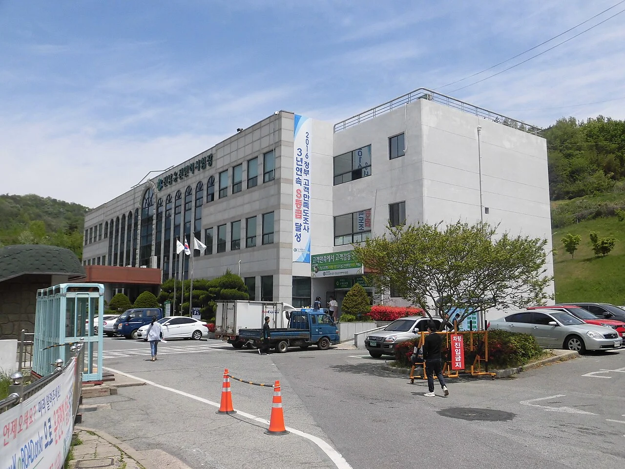전남 운전면허시험장 건물 전경, 언덕을 배경으로 한 회색 건물과 주차된 차량들