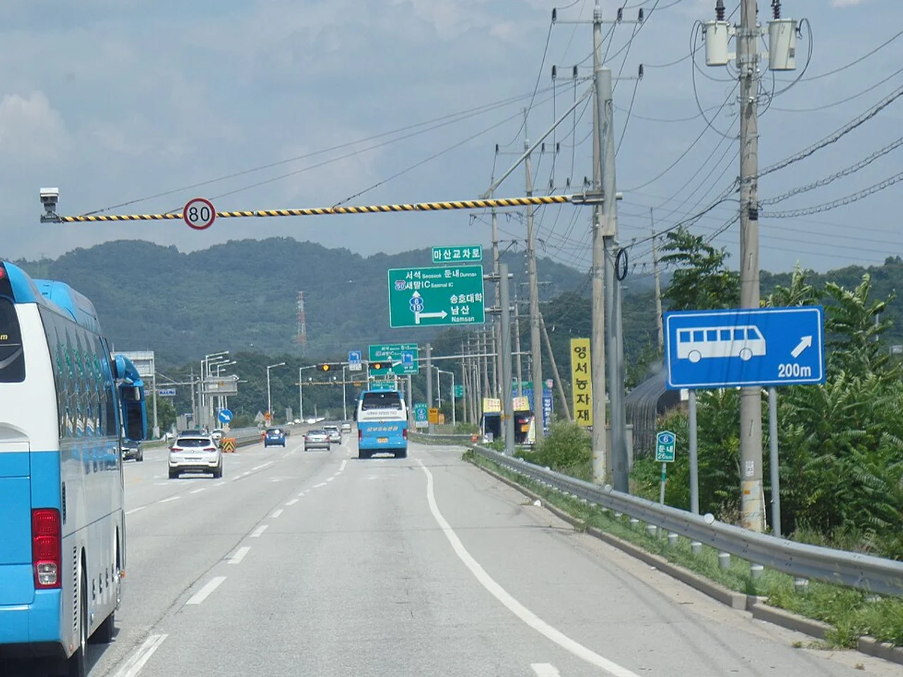 80km/h 제한속도 표지와 단속 카메라가 설치된 국도 구간, 버스와 승용차가 달리는 모습