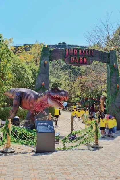 공룡 조형물과 "JURASSIC PARK" 간판이 걸린 공원 입구