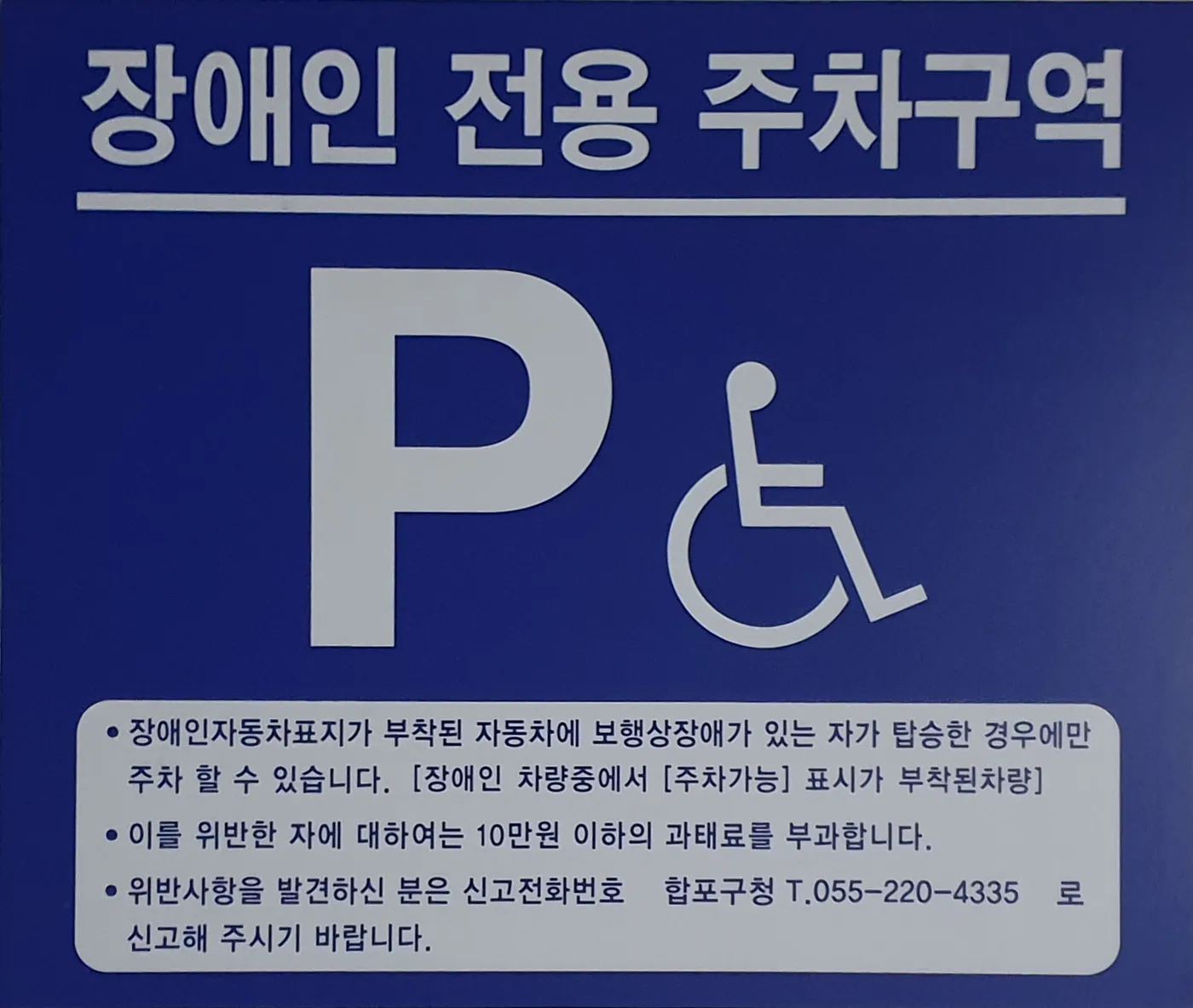 파란 바탕에 흰색 글씨로 장애인 전용 주차구역과 과태료 안내가 적힌 한국의 안내판