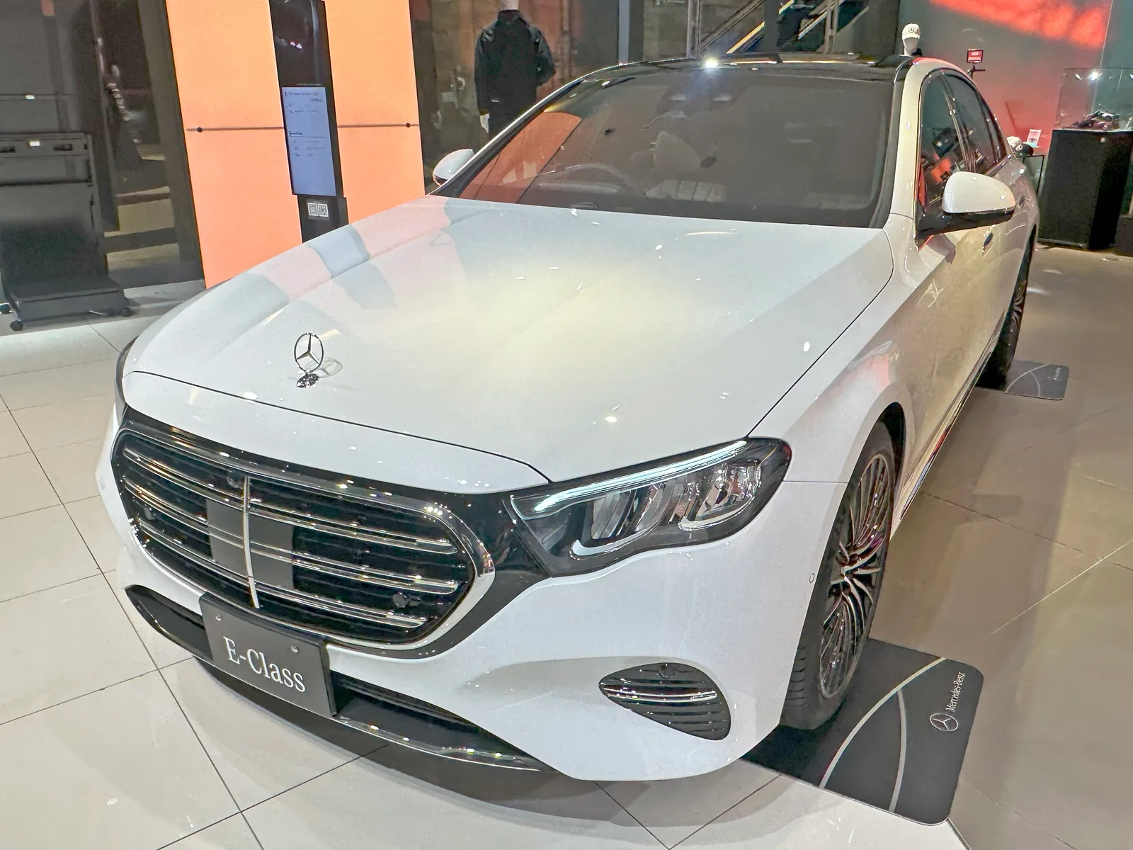 메르세데스-벤츠 전시장에 놓인 흰색 E-Class E200 익스클루시브 차량의 정측면 모습