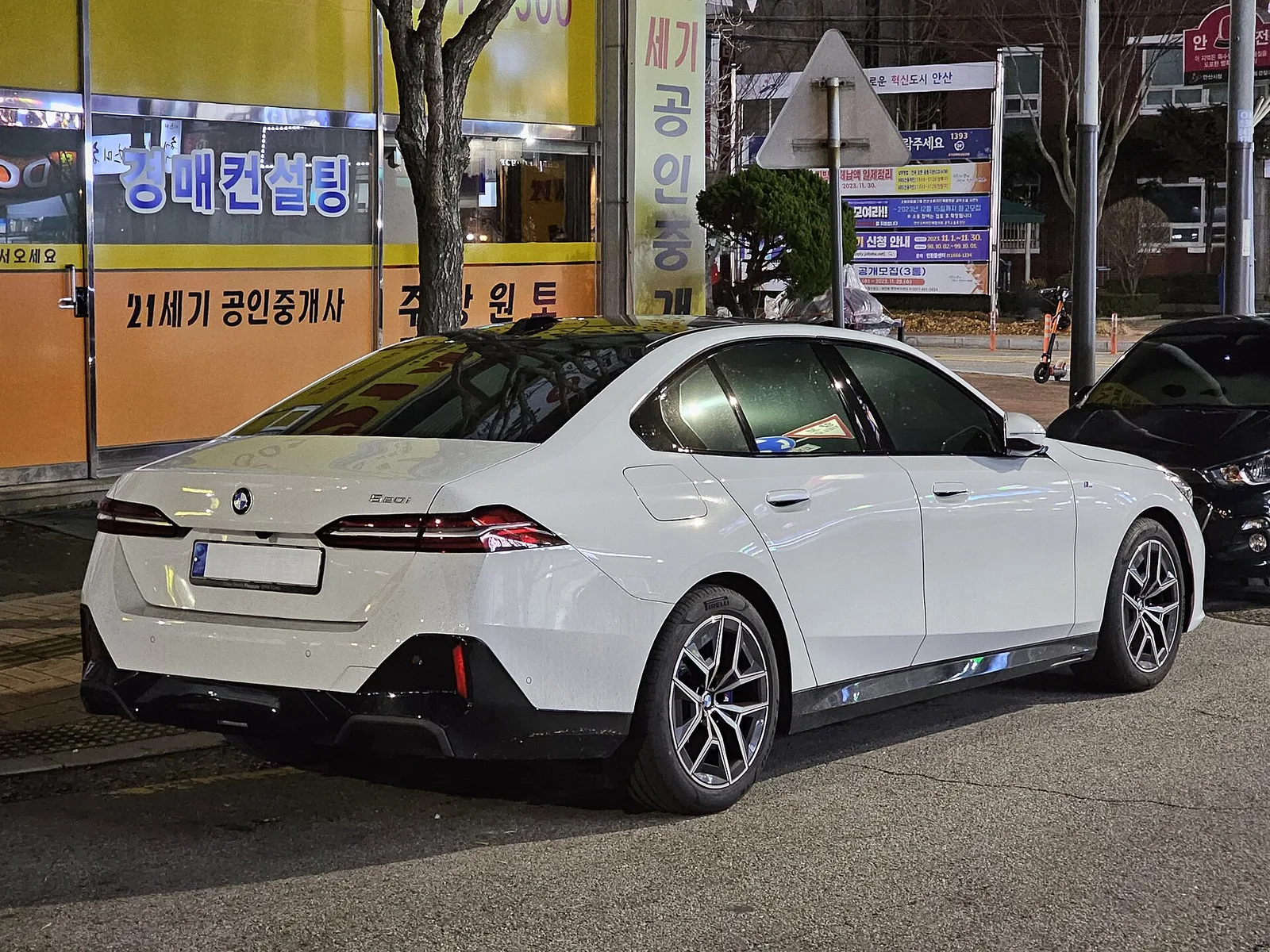 도로변에 세워 둔 흰색 BMW 5시리즈(G60) 세단의 후면 3/4 모습
