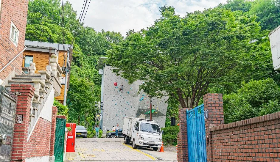 주택가 골목 끝에 인공 암벽이 보이는 진입로