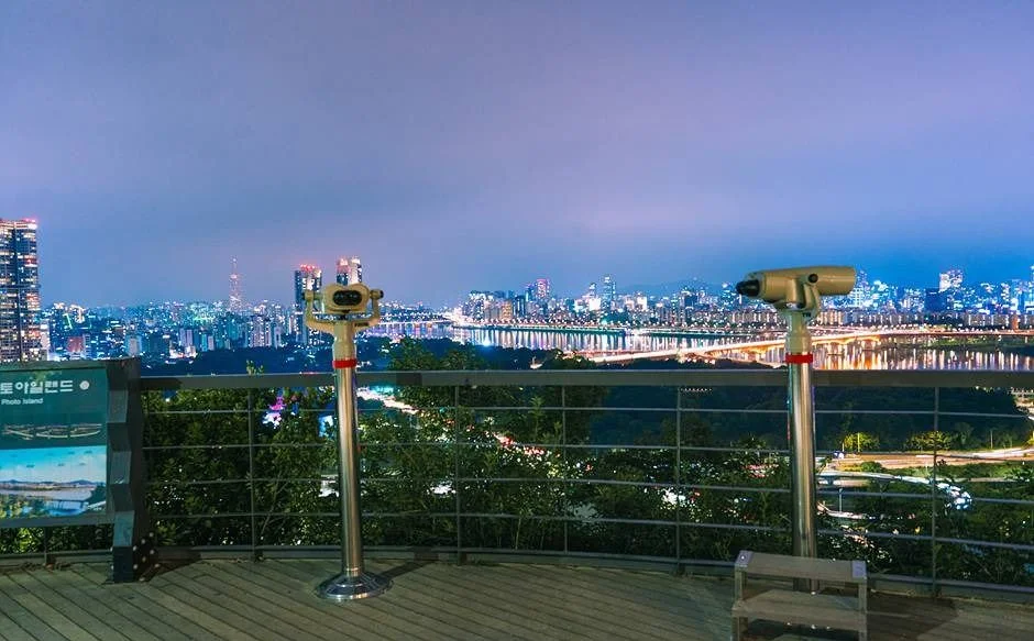 망원경 두 대가 놓인 전망 데크 너머로 서울 야경이 보이는 장면